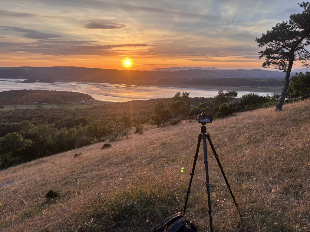 A camera on a tripod overlooking a mountain lake
